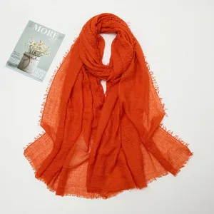 Orange crinkled scarf detail, cotton linen texture with frayed edges, lightweight wrap.