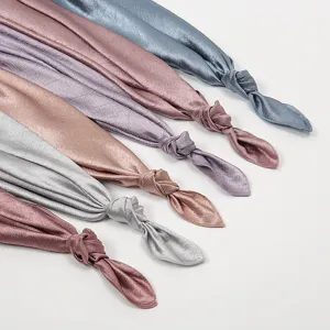 Detail view of crinkled satin long scarves showcasing smooth fabric texture and exquisite knot design.