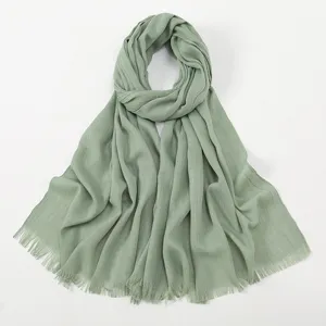Detailed view of sage green slub cotton scarf texture with fringe tassel edge detail.