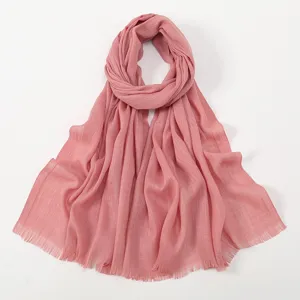 Close-up detail of solid color slub cotton scarf with tassel edge, soft and breathable fabric.