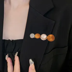 Close-up detail of a chic multi-sphere decorative brooch pinned on a stylish black blazer.