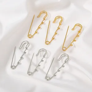 Close-up detail of creative metal safety pin brooch, dual-tone gold and silver decorative loops.