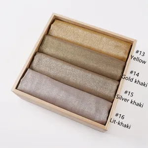Close-up detail of metallic glitter headscarf rolls in wooden box showcasing color options.