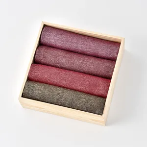 Detailed view of solid color metallic thread women's scarf shawl, rolled neatly in a wooden box.