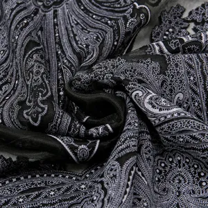 Close-up detail of black and white paisley lace shawl fabric, showing delicate burnt-out texture.