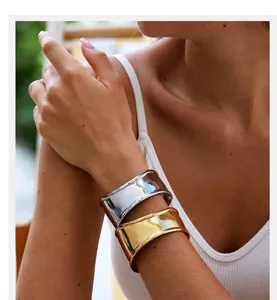 Detalle de pulseras anchas e irregulares en forma de C en color dorado y plateado.
