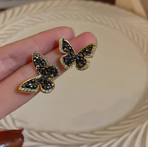 Makrodetail eleganter schwarzer Kristall-Schmetterlings-Ohrstecker in luxuriöser Goldoptik.