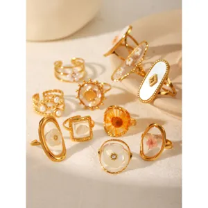 Detail view of gold-plated stainless steel resin rings with pressed flowers and shells
