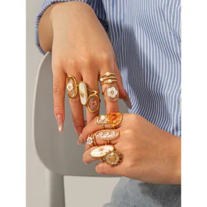 Close-up view of gold stainless steel rings with floral resin and pearl accents on fingers