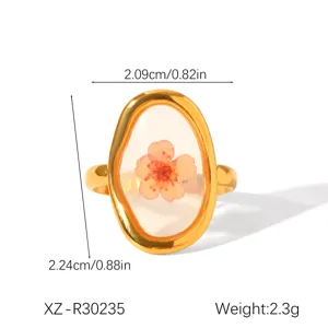 Detailed view of an oval gold stainless steel ring featuring a real dried pink flower.