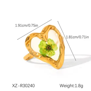 Detailed macro view of heart-shaped ring featuring a green pressed flower and sizes