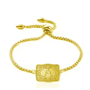 Macro detail of golden embossed rectangular plaque with letter A on box chain bracelet
