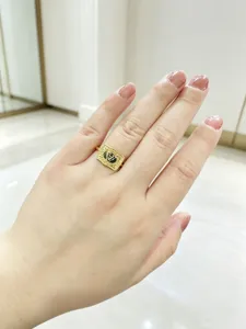 Close-up of an embossed gold buckle ring with a letter pattern worn on a hand.