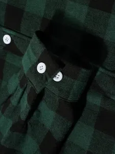 Close-up detail view of mens green and black plaid flannel shirt cuff with white buttons.