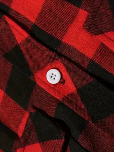 Detailed close-up view of red and black buffalo plaid flannel shirt fabric with white button.