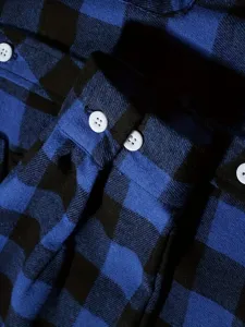 Detailed close-up view of mens blue and black plaid flannel shirt cuff texture.