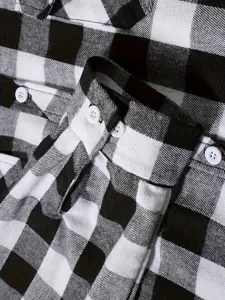 Men flannel plaid shirt detail close-up, classic black and white checked pattern, cuff buttons.