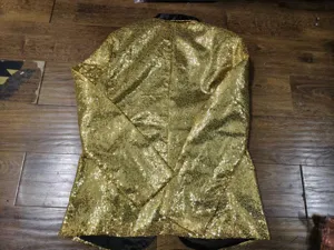 Detailed view of men's gold sequin blazer jacket, showing back and glittering fabric.