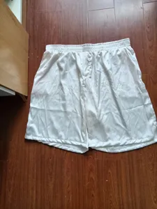 Detail shot of white satin boxer shorts, smooth fabric texture, casual sleepwear style.