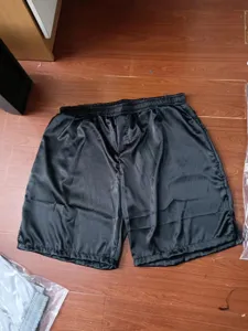 Detailed view of smooth black satin men's boxer shorts, silky texture fabric closeup.