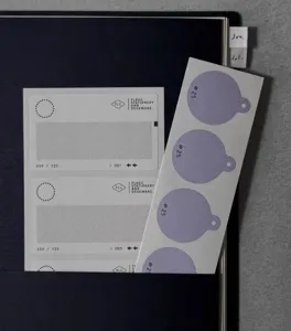 Detailaufnahme von Briefpapier-Aufklebern mit lila runden Etiketten und Rastermusterblättern.
