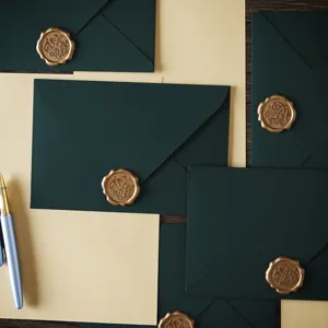 Close-up detail of dark green envelopes with gold wax seals and vintage stationery paper.