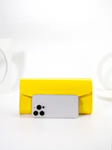 Close-up of bright yellow patent leather envelope clutch bag with clean texture and fine stitching.