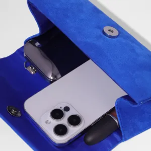 Blue velvet evening clutch bag detail showing spacious interior capacity for phone and essentials.