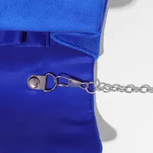 Close-up detail of blue evening clutch interior and silver metal chain strap hardware.