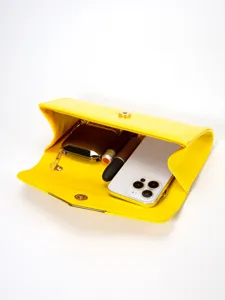 Yellow patent leather envelope clutch bag detail view showing interior capacity with phone.