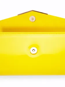 Glossy yellow patent leather envelope clutch bag detail featuring magnetic snap closure.