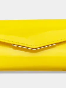 Close-up of bright yellow patent leather envelope clutch detail with metal bar accent.