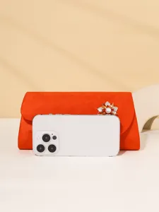 Close-up detail of red suede evening clutch bag featuring a sparkling crystal flower brooch.