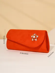 Orange suede evening clutch bag featuring a stunning rhinestone flower pearl brooch accessory.