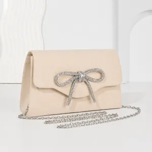 Elegant beige faux suede evening clutch bag featuring a dazzling rhinestone bow and chain.