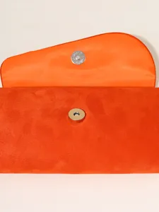 Orange suede evening clutch bag with magnetic snap closure and iconic saddle flap design.