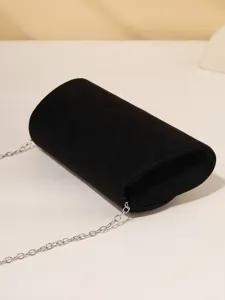 Black velvet cylindrical clutch bag detail view with silver chain strap for elegant evening wear.