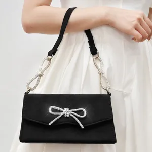 Elegant black suede evening handbag featuring sparkling rhinestone bow and crystal chain strap.