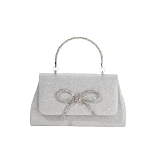 Silver glitter evening handbag with sparkling rhinestone bow and stylish metallic top handle.