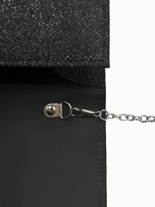Close-up detail of black glitter evening bag interior, metal chain strap and clasp.