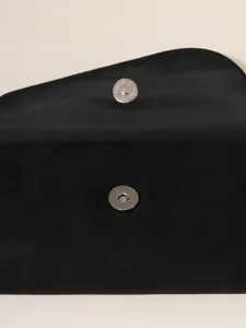 Detailed close-up of a black suede evening clutch featuring a metal magnetic snap closure.