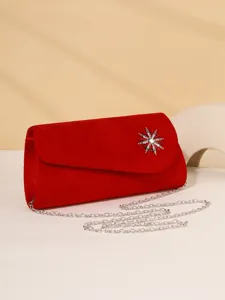 Red velvet evening clutch bag with crystal star brooch and silver chain strap detail.