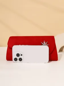 Red suede evening clutch bag detail, exquisite rhinestone brooch accessory, elegant women purse.