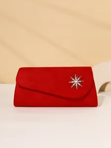 Red suede evening clutch bag detail featuring a sparkling crystal star brooch and soft texture.