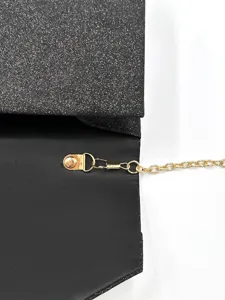 Vista dettagliata della borsa da sera nera glitterata con catena d'oro e chiusura.