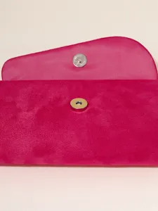 Close-up detail of a vibrant pink velvet evening clutch bag with a secure magnetic snap closure.