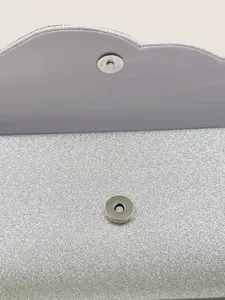 Dettaglio interno di una borsa da sera glitterata argento con chiusura magnetica.