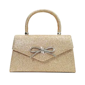 Elegant gold glitter evening handbag featuring a sparkling rhinestone bow and round handle.