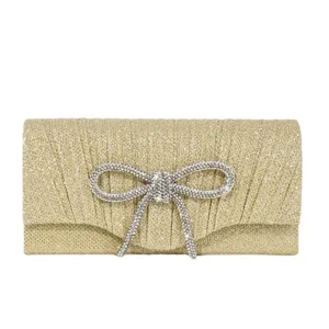 Gold glitter evening clutch bag with rhinestone bow, elegant pleated minibag for party events.