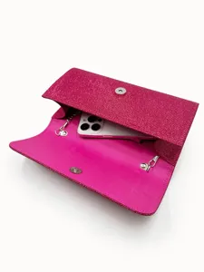 Detailed view of women pink glitter evening clutch bag interior, showing chain links and phone.